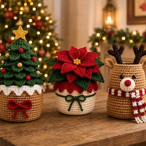 Può includere: Tre contenitori decorativi all'uncinetto a tema natalizio. Uno è un albero di Natale verde con una stella gialla, uno è una stella di Natale rossa e uno è una renna beige con corna marrone scuro e una sciarpa a righe rosse e bianche.