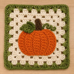 May include: A square crochet granny square featuring a central orange pumpkin with a brown stem and a green leaf. The pumpkin is surrounded by a cream-colored background and framed by a border of dark green crochet stitches in a classic pattern.
