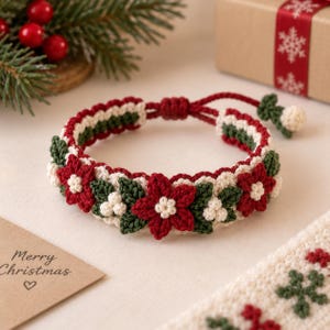 Pode incluir: Uma pulseira de crochê com um padrão repetitivo de flores de poinsétia vermelhas, folhas verde-escuras e pequenas bagas brancas. A pulseira tem um fecho de cordão ajustável com uma pequena flor decorativa, feita com fio vermelho, verde e creme.