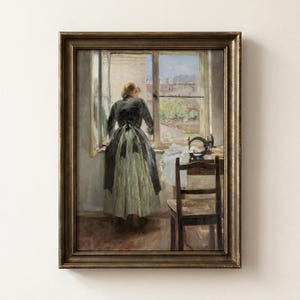 May include: A framed oil painting depicting a person standing at an open window, wearing a dark long-sleeved top and a light green skirt. A sewing machine sits on a wooden table next to a wooden chair, with a view of city buildings in the distance.