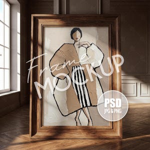 May include: A rectangular wooden frame containing an abstract painting of a figure wearing a tan and white coat over a black and white striped skirt. The text Frame MOCKUP is overlaid on the image, with a circular PSD JPG & PNG badge.