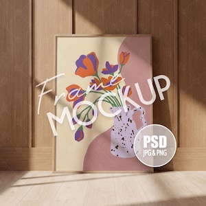 May include: A rectangular wooden frame containing a print of a light purple speckled pitcher holding orange and purple flowers against a background of cream and dusty rose shapes. The text Frame MOCKUP is overlaid in white, with a circular PSD JPG & PNG badge.
