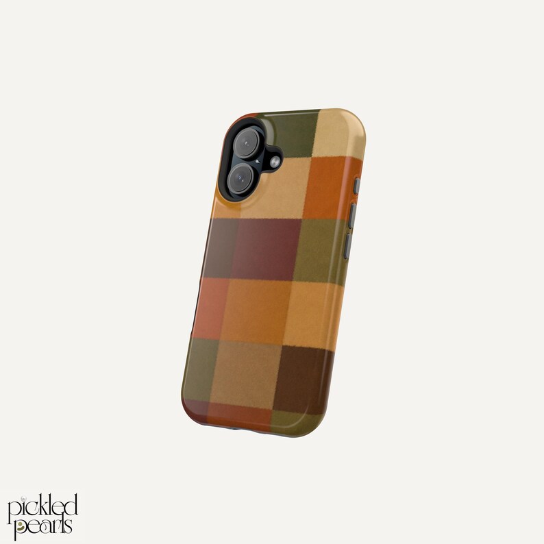 Peut inclure: Une coque de smartphone avec un motif &agrave; carreaux multicolores dans des tons vert olive, orange br&ucirc;l&eacute;, jaune moutarde et brun fonc&eacute;. La coque pr&eacute;sente un bloc cam&eacute;ra noir avec deux objectifs circulaires et un flash, avec le texte Pickled Pearls.