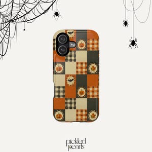 Könnte beinhalten: Eine rechteckige Handyhülle mit einem Patchwork-Design aus orangefarbenen, schwarzen und cremefarbenen Quadraten. Das Muster umfasst Karomuster, einfarbige Flächen und kreisförmige Motive mit Illustrationen von Kürbissen, Fledermäusen und Herbstblättern.