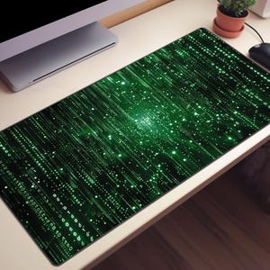 Puede incluir: Una alfombrilla de escritorio rectangular con un patrón de matriz digital que presenta flujos verticales de código binario verde, puntos de datos brillantes y símbolos abstractos sobre un fondo negro, creando un diseño visual de alto contraste.