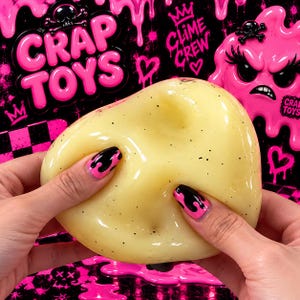 Puede incluir: Una masilla semisólida, translúcida y de color amarillo pálido con pequeñas motas negras. El fondo presenta gráficos de slime rosa brillante que gotea, un patrón de cuadros negro y rosa, y el texto CRAP TOYS y CLIME CREW con iconos de calaveras.