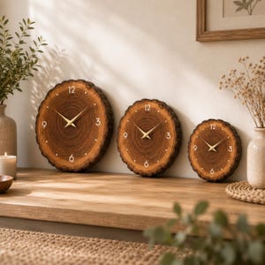 Può includere: Tre orologi da parete circolari realizzati con fette di legno naturale con anelli di crescita visibili e bordi in corteccia. Ogni orologio presenta un quadrante in legno marrone scuro, lancette color oro e numeri bianchi.