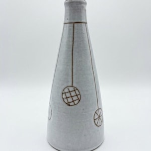 May include: A tall, conical ceramic vase with a light grey, speckled glaze. The surface is decorated with thin, brown hand-drawn lines forming vertical stems that lead to circular patterns, including a grid design and a radial spoke motif.