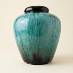 May include: A rounded ceramic vessel featuring a glossy finish with a gradient of deep teal and turquoise hues that transition into a dark, near-black base. The piece is topped with a smooth, solid black lid that sits flush against the opening.