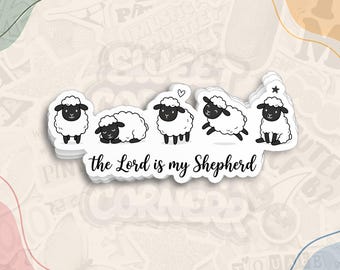 May include: A white die-cut sticker featuring five black and white cartoon sheep in various poses, with the black text "the Lord is my Shepherd" written in a cursive script underneath the sheep illustrations.