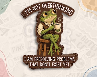 May include: A die-cut sticker featuring a green frog wearing round glasses and a brown vest, sitting on a wooden stool while holding a steaming mug. The text reads I'M NOT OVERTHINKING and I AM PRESOLVING PROBLEMS THAT DON'T EXIST YET.