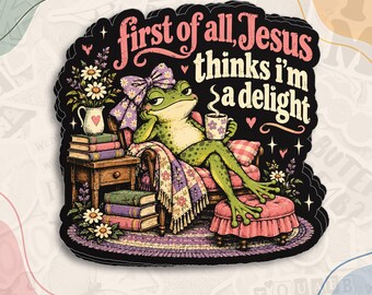 May include: A die-cut sticker featuring a green frog wearing a purple patterned bow, sitting in an armchair with a mug and books. The text reads, first of all, Jesus thinks i'm a delight. The design includes a side table, flowers, and a footstool.