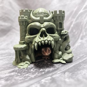 May include: A light green, 3D-printed skull castle hideout featuring two side towers, a central dome, and a coiled snake sculpture on the right side. A small, brown, patterned gecko is visible inside the dark, hollow skull mouth opening.