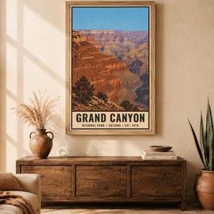 K&ouml;nnte beinhalten: Ein vertikaler Wandkunstdruck mit einer Landschaftsillustration des Grand Canyon mit geschichteten roten Felsformationen unter einem klaren blauen Himmel. Der Text unten lautet GRAND CANYON NATIONAL PARK ARIZONA EST. 1919 in schwarzer Schrift.