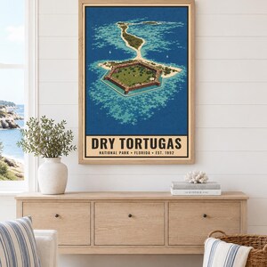 May include: A framed vertical poster featuring an aerial illustration of the hexagonal Fort Jefferson surrounded by turquoise water and sandy islands. The text reads DRY TORTUGAS NATIONAL PARK FLORIDA EST. 1992. The print is displayed in a light wood frame.