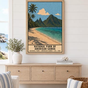 May include: A framed vertical poster depicting a tropical beach scene with palm trees, a sandy shore, turquoise water, and dark green mountains under a blue sky. The text reads NATIONAL PARK OF AMERICAN SAMOA NATIONAL PARK AMERICAN SAMOA EST. 1988.