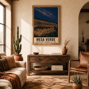 May include: A rectangular wall art print featuring a night sky filled with stars above the cliff dwellings of Mesa Verde National Park, Colorado. The poster includes the text MESA VERDE NATIONAL PARK COLORADO EST. 1906 in a bold font.