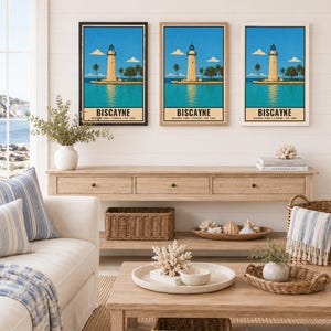 May include: Three framed wall art prints featuring a vintage-style illustration of the Biscayne National Park lighthouse in Florida. The artwork depicts a tan lighthouse on a small island surrounded by blue water, palm trees, and a clear sky.