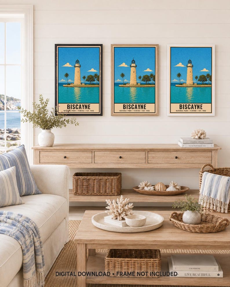 May include: Three framed wall art prints featuring a vintage-style illustration of the Biscayne National Park lighthouse in Florida. The artwork depicts a tan lighthouse on a small island surrounded by blue water, palm trees, and a clear sky.