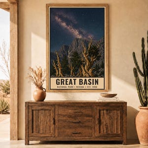 May include: A rectangular wall art print featuring a night sky with a visible Milky Way galaxy above rugged mountain peaks and twisted bristlecone pine trees. The bottom section contains the text GREAT BASIN NATIONAL PARK NEVADA EST. 1986.
