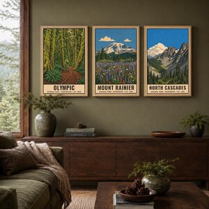 Może przedstawiać: Trzy pionowe wydruki artystyczne w jasnych drewnianych ramach z ilustracjami park&oacute;w narodowych Olympic, Mount Rainier i North Cascades. Każdy wydruk przedstawia krajobraz z tekstem na dole. Plik cyfrowy do pobrania, ramka nie jest dołączona.