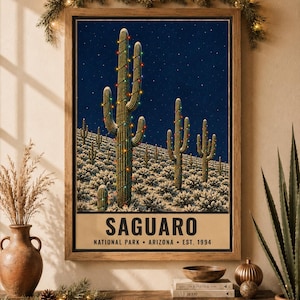 May include: A framed wall art print featuring a desert landscape at night with saguaro cacti wrapped in colorful string lights under a starry sky. The text at the bottom reads SAGUARO NATIONAL PARK ARIZONA EST. 1994 in a bold, dark font.