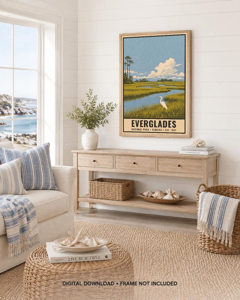 K&ouml;nnte beinhalten: Ein vertikaler Wandkunstdruck mit einer stilisierten Landschaft des Everglades-Nationalparks in Florida. Die Illustration zeigt ein sumpfiges Gew&auml;sser mit hohem Gras, einen wei&szlig;en Vogel und einen blauen Himmel mit Wolken. Der Text lautet EVERGLADES.