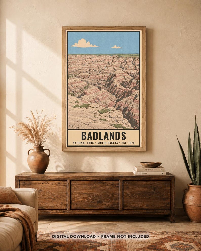May include: A vertical wall art print featuring a landscape illustration of the Badlands National Park in South Dakota. The print displays layered rock formations under a blue sky with clouds and includes the text BADLANDS NATIONAL PARK SOUTH DAKOTA EST. 1978.