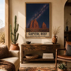 May include: A rectangular wall art print featuring a night sky filled with stars and the Milky Way above red rock formations in Capitol Reef National Park, Utah. The text at the bottom reads CAPITOL REEF NATIONAL PARK UTAH EST. 1971.