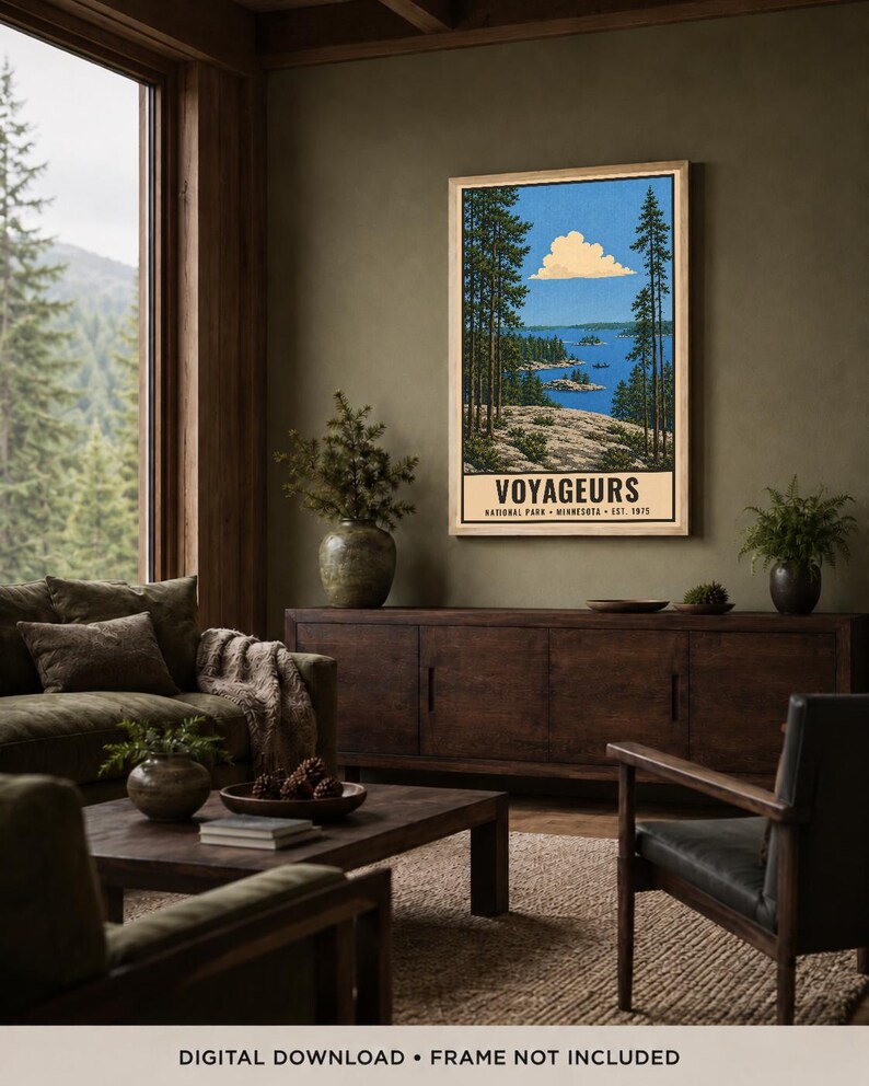 Op de afbeelding: Een ingelijste verticale poster met een landschapsillustratie van Voyageurs National Park in Minnesota. Het kunstwerk toont een blauw meer met rotsachtige eilanden, hoge dennenbomen op de voorgrond en een wolk in een blauwe lucht.