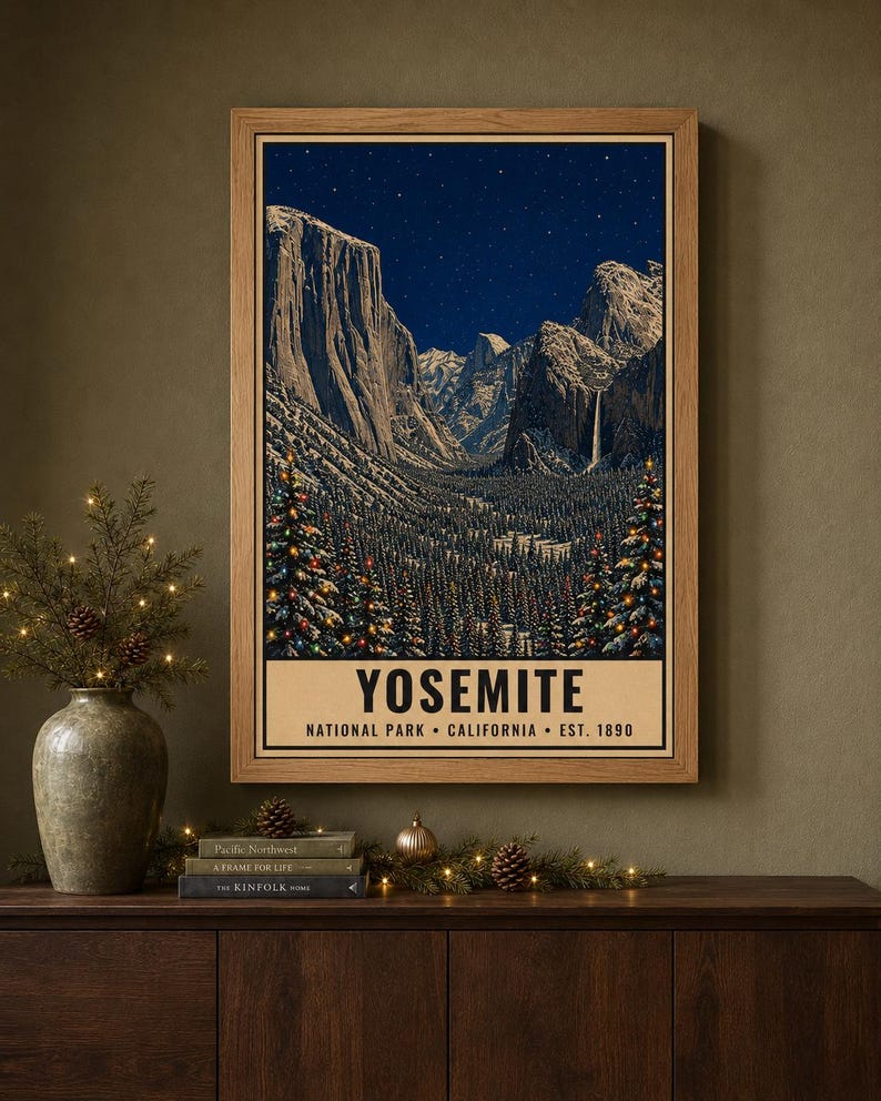 May include: A framed vertical poster depicting a night scene of Yosemite National Park with snow-covered mountains, a starry sky, and evergreen trees decorated with colorful lights. The text reads YOSEMITE NATIONAL PARK CALIFORNIA EST. 1890.