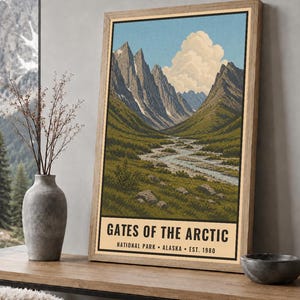 Może przedstawiać: Pionowy, prostokątny plakat z ilustracją krajobrazu Parku Narodowego Gates of the Arctic na Alasce. Grafika przedstawia poszarpane g&oacute;ry, wijącą się rzekę i dużą chmurę na tle błękitnego nieba, z napisem GATES OF THE ARCTIC NATIONAL PARK ALASKA EST. 1980 u dołu.