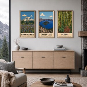Op de afbeelding: Drie verticale wandkunstprints met illustraties van de nationale parken Mount Rainier, Crater Lake en Olympic. Elke print toont een landschap met tekst onderaan die het park, de staat en het oprichtingsjaar identificeert.