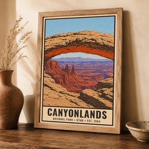 Może przedstawiać: Oprawiony plakat ze stylizowaną ilustracją łuku Mesa Arch w Parku Narodowym Canyonlands w stanie Utah. Grafika przedstawia czerwone formacje skalne pod niebieskim niebem, z napisem CANYONLANDS NATIONAL PARK UTAH EST. 1964 u dołu.