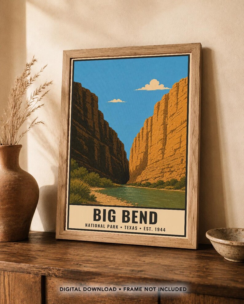 Op de afbeelding: Een ingelijste kunstdruk met een landschapsillustratie van Big Bend National Park in Texas. De afbeelding toont een rivier die stroomt tussen hoge, oranjebruine canyonwanden onder een helderblauwe lucht met twee kleine wolken en tekst onderaan.
