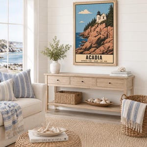 May include: A vertical wall art print featuring a lighthouse on a rocky cliffside overlooking the ocean. The text reads ACADIA NATIONAL PARK MAINE EST. 1919. The illustration uses a palette of blue, white, and earthy brown tones in a vintage style.