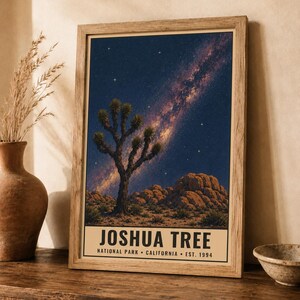 May include: A framed vertical poster featuring a night landscape of Joshua Tree National Park with a starry sky and a prominent Milky Way galaxy. The text at the bottom reads JOSHUA TREE NATIONAL PARK CALIFORNIA EST. 1994 in black font.