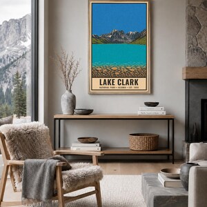 Pode incluir: Uma impress&atilde;o de arte de parede retangular vertical com uma paisagem estilizada do Parque Nacional Lake Clark no Alasca. A ilustra&ccedil;&atilde;o mostra montanhas cobertas de neve, um c&eacute;u azul brilhante, um lago turquesa e o texto LAKE CLARK.