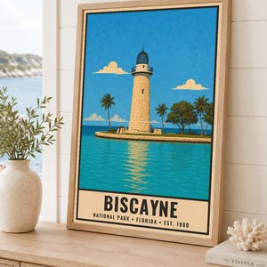 May include: A framed travel poster print featuring a stone lighthouse on a small island surrounded by turquoise water under a bright blue sky. The text at the bottom reads BISCAYNE NATIONAL PARK FLORIDA EST. 1980 in a bold black sans-serif font.