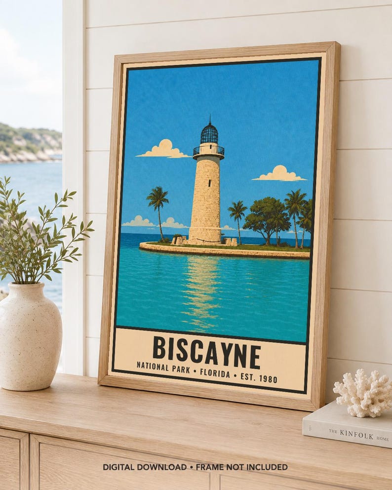 May include: A framed travel poster print featuring a stone lighthouse on a small island surrounded by turquoise water under a bright blue sky. The text at the bottom reads BISCAYNE NATIONAL PARK FLORIDA EST. 1980 in a bold black sans-serif font.