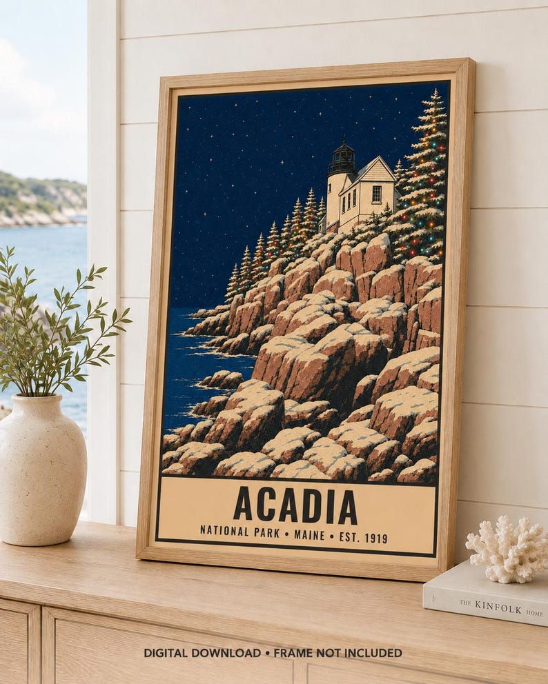 Puede incluir: Un p&oacute;ster enmarcado con una ilustraci&oacute;n nocturna de un faro en un acantilado rocoso en el Parque Nacional Acadia, Maine. La escena incluye rocas cubiertas de nieve, &aacute;rboles de hoja perenne con luces y un cielo estrellado. El texto dice ACADIA.