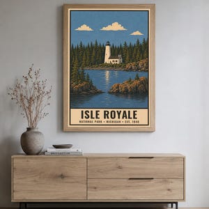 Op de afbeelding: Een verticale poster met een witte vuurtoren op een rotsachtige kustlijn, omringd door een dicht bos en blauw water onder een heldere lucht. De tekst onderaan luidt ISLE ROYALE NATIONAL PARK MICHIGAN EST. 1940 in vetgedrukte zwarte letters.