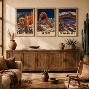 May include: Three vertical wall art prints featuring winter landscapes of Bryce Canyon, Arches, and Canyonlands National Parks. Each print displays snow-covered rock formations, starry night skies, and decorated Christmas trees with text.