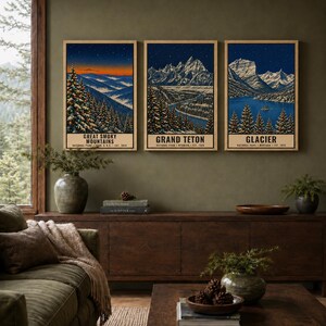 May include: A set of three vertical art prints featuring illustrations of Great Smoky Mountains, Grand Teton, and Glacier national parks. Each print displays a snowy mountain landscape at night under a starry sky with text at the bottom.