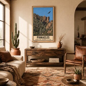 Op de afbeelding: Een verticale rechthoekige wandkunstprint met een landschap van Pinnacles National Park, Californi&euml;, met rotsachtige pieken, groene bomen, een blauwe lucht en een vliegende vogel. De tekst luidt PINNACLES NATIONAL PARK CALIFORNIA EST. 2013.