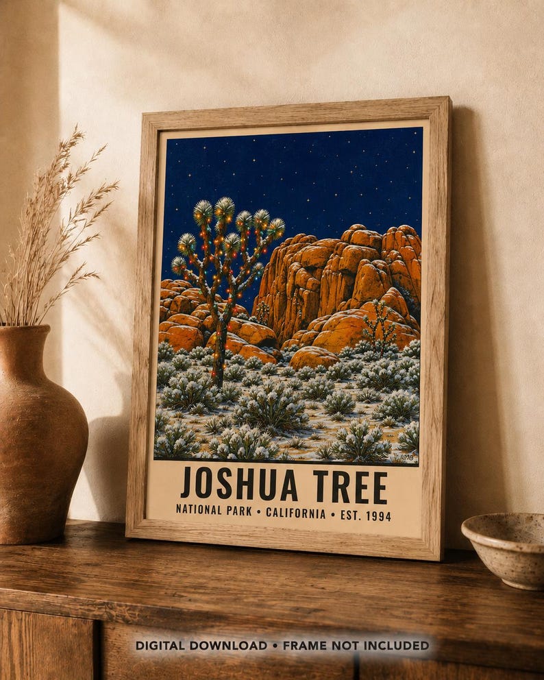 May include: A framed art print featuring a night scene of Joshua Tree National Park with a starry sky, orange rock formations, and a Joshua tree decorated with lights. The text reads JOSHUA TREE NATIONAL PARK CALIFORNIA EST. 1994.