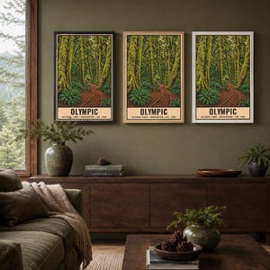 Może przedstawiać: Trzy pionowe wydruki ścienne przedstawiające leśną scenerię z omszałymi drzewami i polną ścieżką, z napisem OLYMPIC NATIONAL PARK WASHINGTON EST. 1938. Wydruki są prezentowane w czarnych, jasnych drewnianych i białych ramach na oliwkowej ścianie.