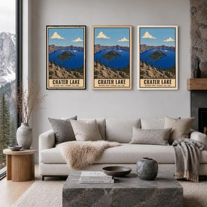 Może przedstawiać: Trzy pionowe wydruki ścienne przedstawiające ilustrację krajobrazu Parku Narodowego Crater Lake w Oregonie. Każdy wydruk ukazuje głębokie niebieskie jezioro, skaliste klify, wiecznie zielone drzewa oraz jasnoniebieskie niebo z chmurami, z napisem Crater Lake.
