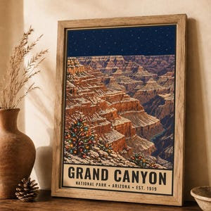 May include: A framed poster featuring a nighttime illustration of the Grand Canyon with snow-dusted rock formations and a pine tree decorated with colorful lights. The text reads GRAND CANYON NATIONAL PARK ARIZONA EST. 1919.