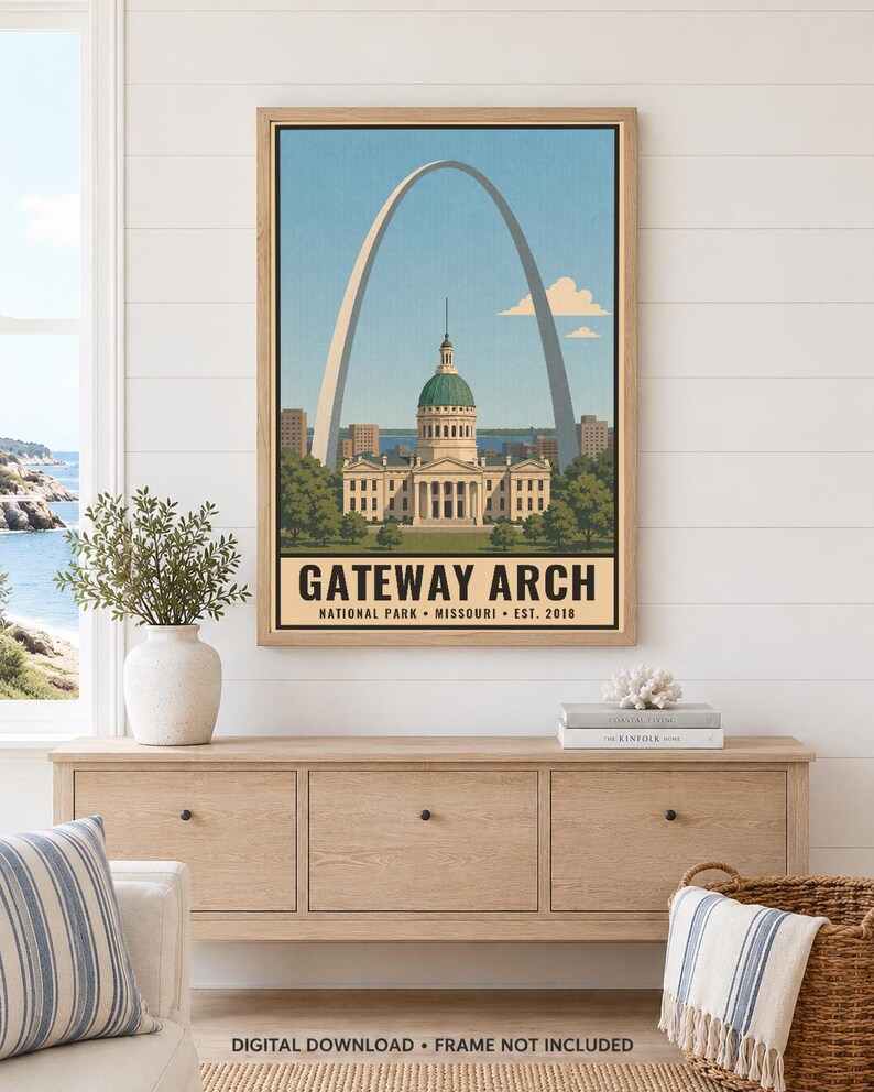 Op de afbeelding: Een ingelijste wandkunstprint met een gestileerde illustratie van de Gateway Arch en het Old Courthouse in St. Louis, Missouri. De tekst luidt GATEWAY ARCH NATIONAL PARK MISSOURI EST. 2018. De print heeft een lichtblauwe lucht.